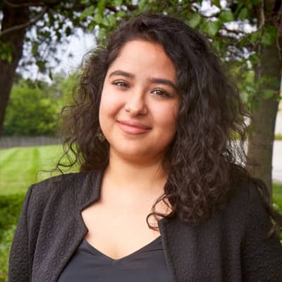 Adilene Osnaya, a woman with dark curly hair, is pictured in a black jacket and shirt.