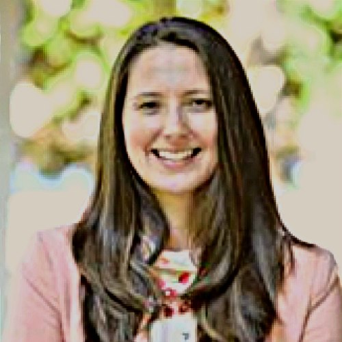 Shannon Savell, M.A., a researcher at the University of Virginia, smiling in an outdoor setting with sunlight filtering through trees in the background.